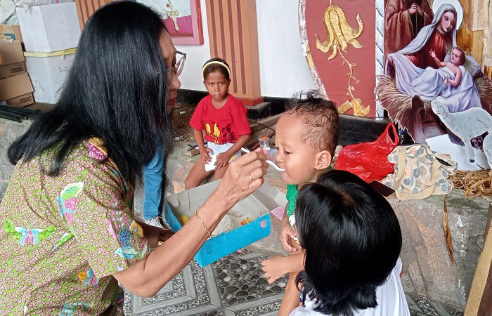 Wakil Ketua I DPP Paroki Katedral Reinha Rosari Larantuka, Apolonia Corebima Secara Simbolis Menyuapi Salah Satu Anak Balita, Sabtu (21/12/2024).