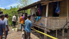 Polisi dibantu warga memasang garis polisi pada pondok  tempat penemuan jenazah seorang pelaljar yang meninggal tidak wajar.