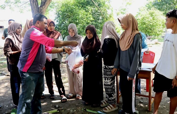 Kepsek SMA Negeri 1 Nangapanda, Simon Lowa, S.Pd (kiri) menyerahkan daging qurban kepada warga yang berhak menerimanya, Rabu (27/5/2026).